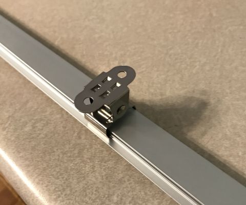 1995 Ford Bronco - A close-up view of a metal clip mounted on an aluminum rail, the Supermotors.net logo in the lower right corner.