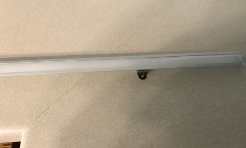 1995 Ford Bronco - A close-up view of an interior trim piece with a mounting bracket, against a textured wall surface.