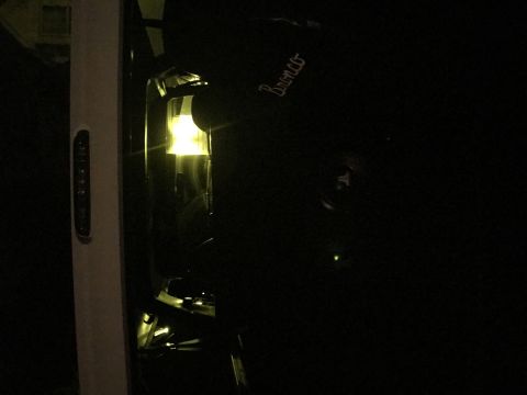 1995 Ford Bronco - A dark photo shows the side of a Ford Bronco with its headlight on.