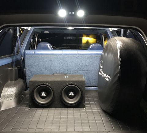 1995 Ford Bronco - Interior view of a 1995 Ford Bronco's cargo area, showing a subwoofer and spare tire cover.