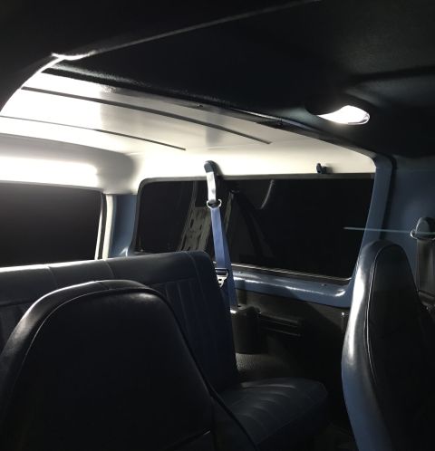 1995 Ford Bronco - The interior of the vehicle features blue upholstered seats and a dark headliner with interior lights.