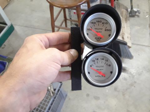 1985 Ford Bronco - A hand holds a dual gauge cluster with differential temperature and voltage readings.
