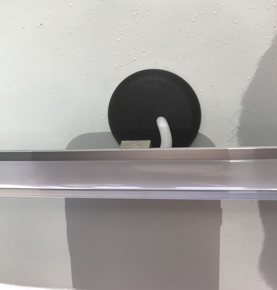 Close-up of a black circular clip with a white plastic piece attached to a metal trim piece on a car door