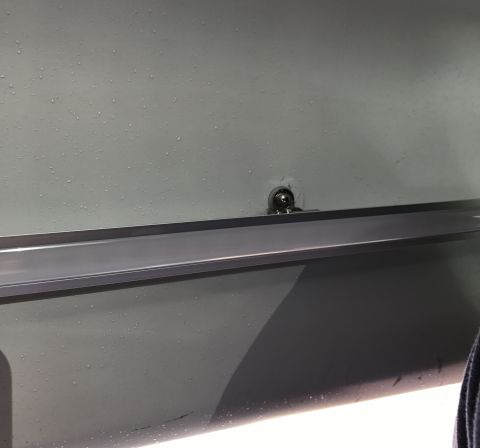 1995 Ford Bronco - A close-up view of a detail on a vehicle's interior panel, showing a metal accent strip and a fastener.