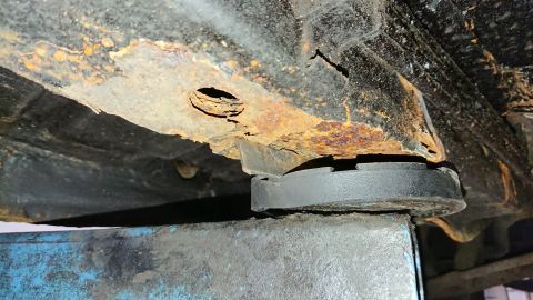 1999 Ford Fairlane - Heavily rusted vehicle frame section, showing significant corrosion and structural damage.