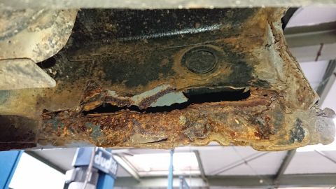 1999 Ford Fairlane - The underside of a vehicle shows extensive rust damage and structural compromise.