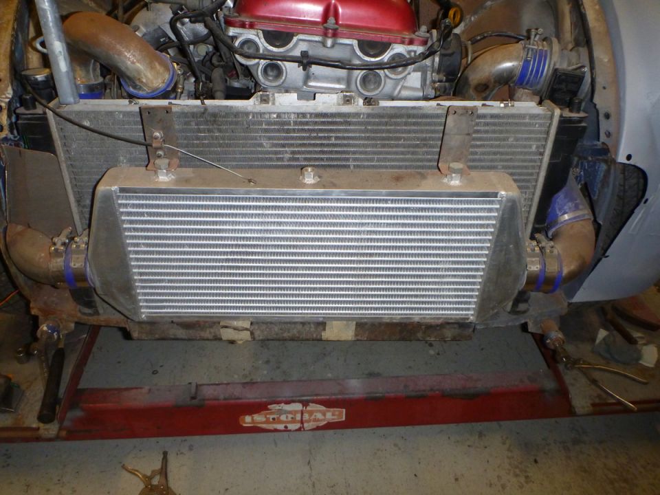 Engine bay with intercooler, radiator, and red-top engine. Blue hose clamps visible