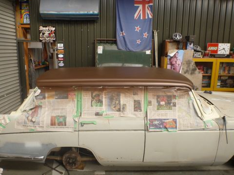 1962 MG B - A car is being prepped for painting, with its windows covered and a new brown roof fitted.