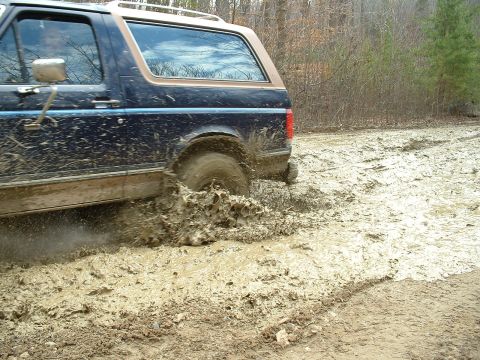 1987 Ford Bronco - This 1987 Ford Bronco navigates a muddy trail, kicking up dirt and water.