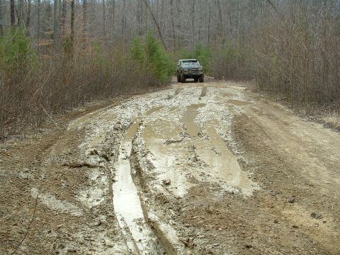 1987 Ford Bronco - Vehicle navigating a challenging muddy trail in the woods.