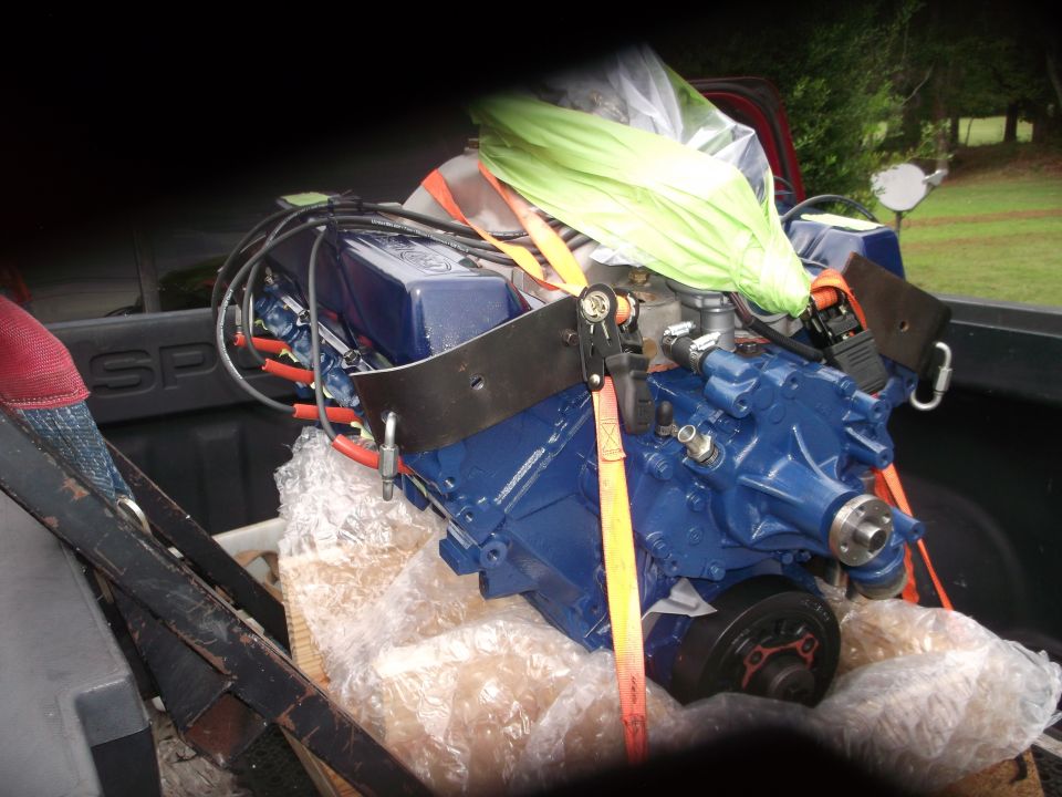 Blue engine with orange straps and green tarp in a truck bed