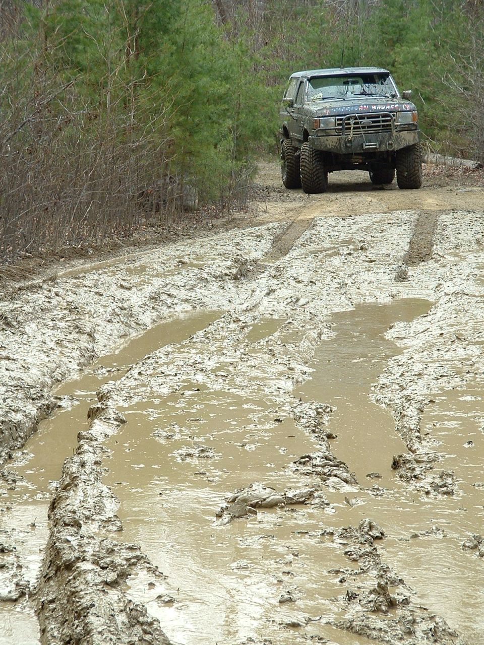 Ford Bronco driving through a muddy trail