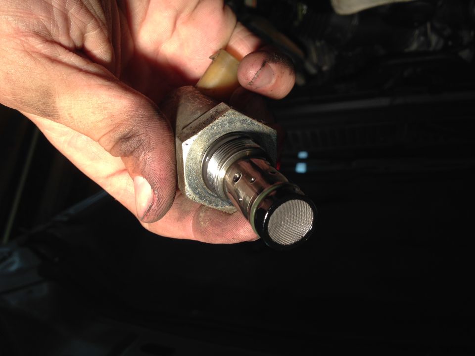 Hand holding a metal fuel pressure regulator with a mesh filter