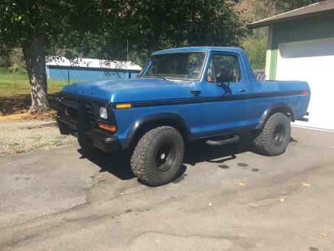 1979 Ford Bronco - This blue Ford Bronco is parked outside a residential garage on a sunny day.