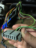 1988 Ford Bronco - Close-up of a hand holding a gray wiring harness connector with numerous colored wires attached.