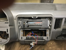 1988 Ford Bronco - The interior of a vehicle shows the dashboard with climate controls and wiring exposed in the center console area.