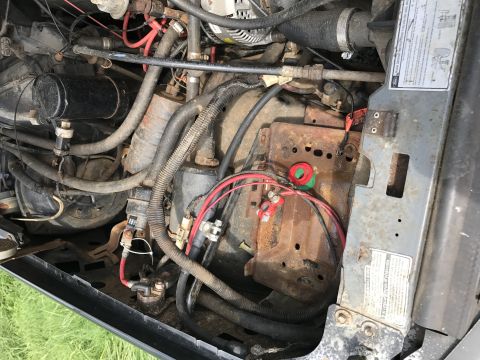 1992 Ford Bronco - Close-up view of the engine bay, focusing on the battery and associated wiring. Some components show signs of age and corrosion.