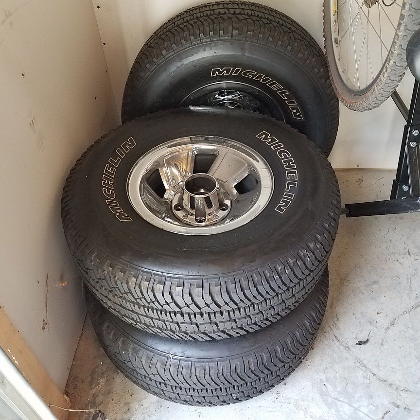Stack of three Michelin tires with chrome rims, one tire visible on top