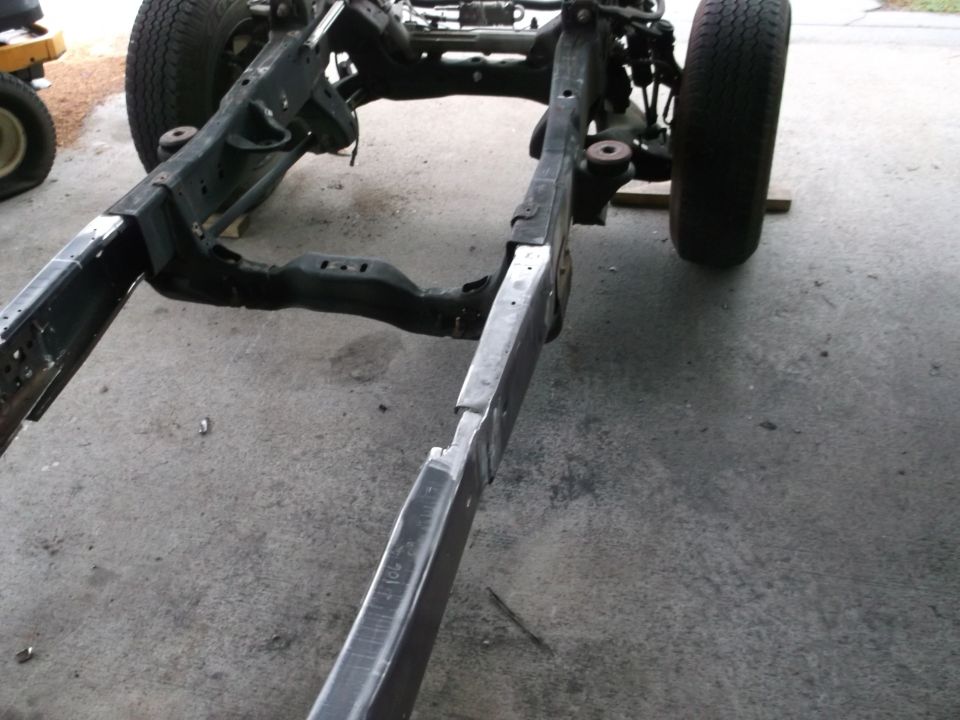 Stripped 1999 Ford Ranger frame on blocks, rear rails ground to bare metal, axle and wheels attached