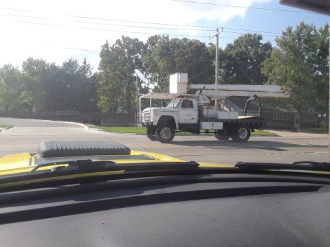 1994 Ford Bronco - A white utility truck with a boom lift is seen from the perspective of another vehicle.