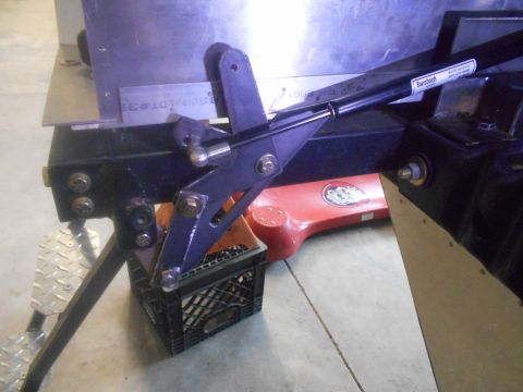 1992 Ford Bronco - A close-up view of a black metal bracket assembly with visible bolts and a red object in the background.