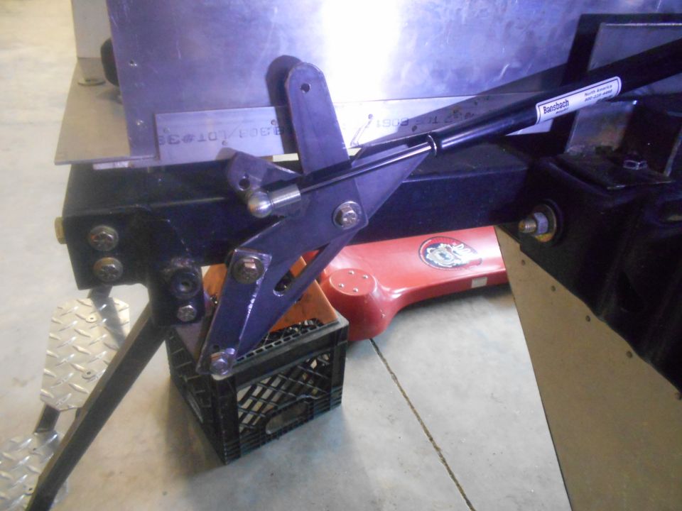 Black metal bracket assembly with bolts and a red object underneath