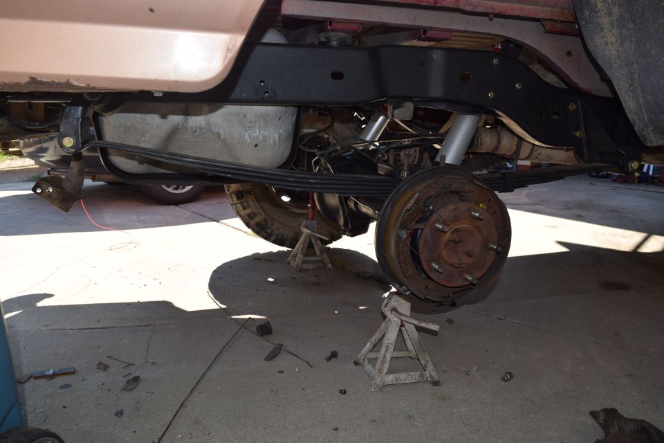 1995 Ford Bronco rear axle assembly with leaf springs and shocks removed, vehicle supported by jack stands