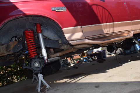 1995 Ford Bronco - The front suspension of a red Ford Bronco is disassembled, with upgraded red shocks and springs installed.