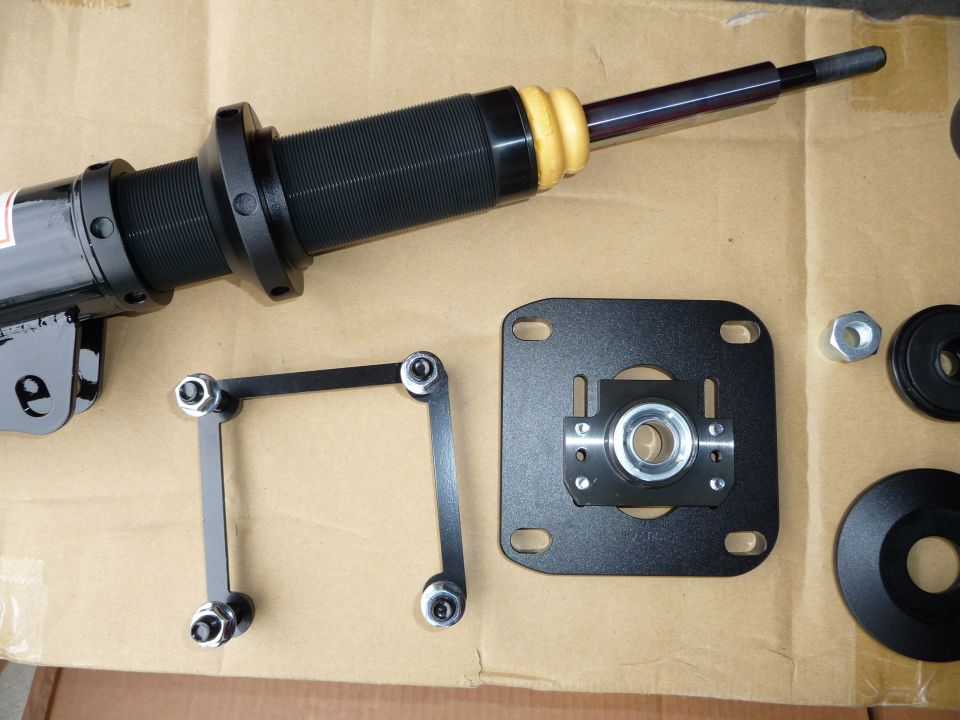 Car suspension strut and mounting hardware laid out on cardboard