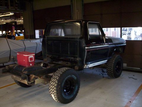 1978 Ford Bronco - A black pickup truck chassis is shown from the side, with a red cooler placed on the fuel tank.