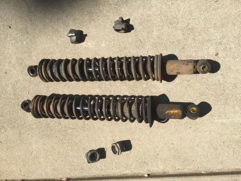 1988 Ford Bronco - Two used shock absorbers and mounting hardware are laid out on a concrete surface, with a Supermotors.net watermark visible.