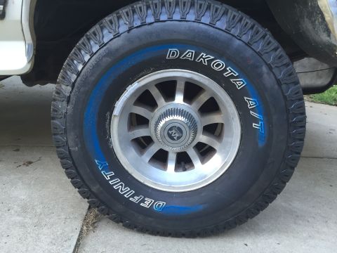 1988 Ford Bronco - This image shows a close-up of a tire and wheel assembly, 'Dakota A/T' and 'Definity' branding on the tire.