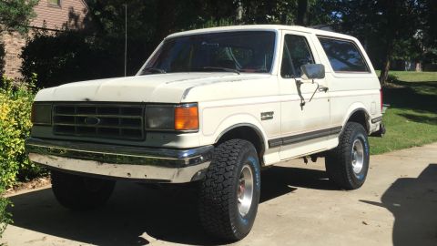 1988 Ford Bronco - This 1988 Ford Bronco is parked on a driveway with trees and a house in the background.