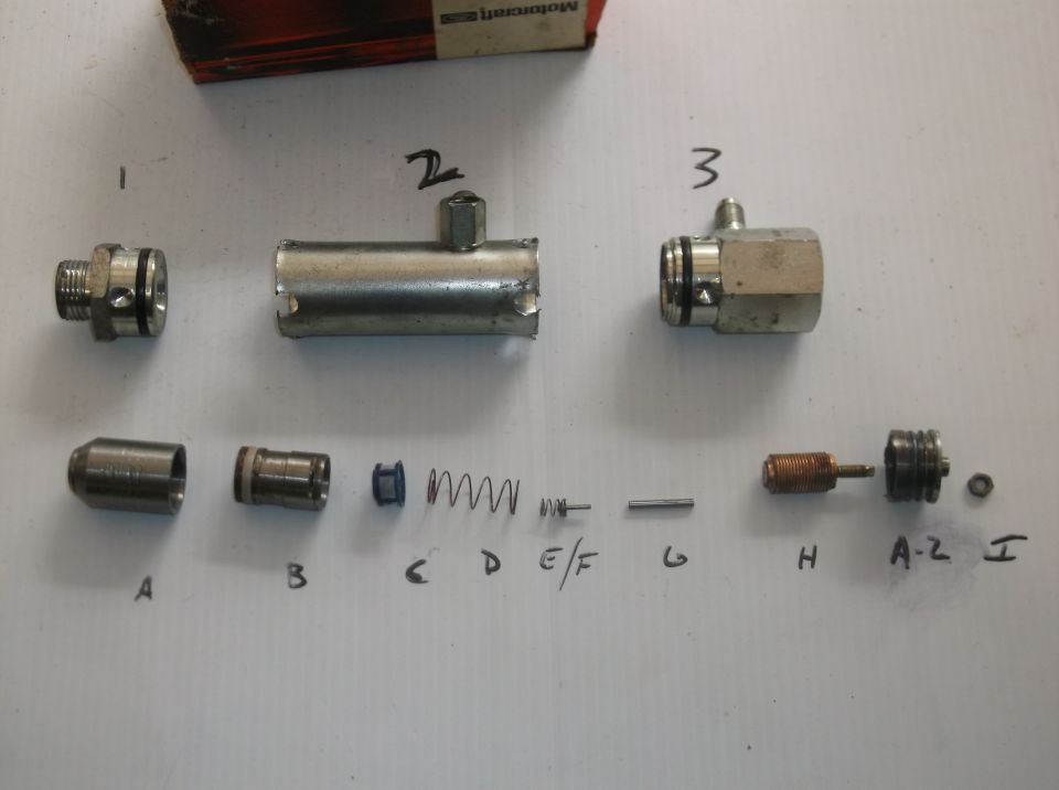 Disassembled brake master cylinder components labeled A through I, with a Motorcraft box in the background
