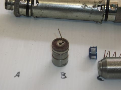 1979 Ford Ranchero - Disassembled engine components, including a valve lifter, are laid out on a white surface.