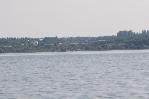 1993 Ford Bronco - A wide shot of a calm lake with a distant tree-lined shore dotted with houses and buildings.