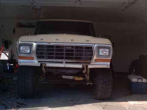 1979 Ford Bronco - Front view of a lifted 1979 Ford Bronco with aftermarket bumper and large tires, parked inside a garage.