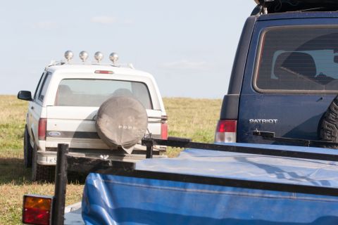 1993 Ford Bronco - The rear of a white Ford Bronco is parked next to a dark blue Patriot SUV. A spare tire is mounted on the back of the Bronco, and a blue ta…