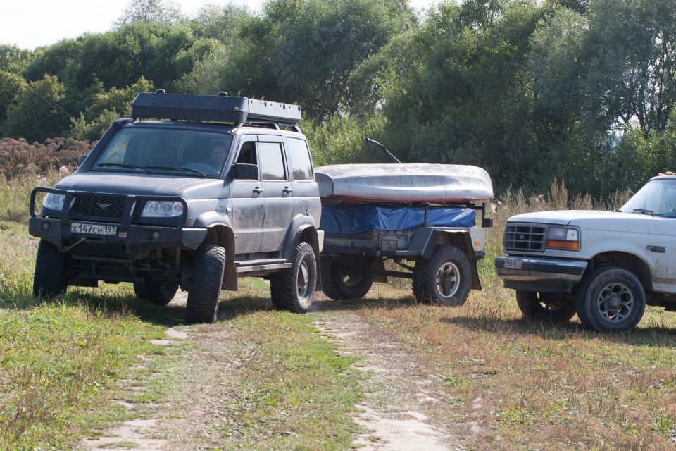 Dark gray SUV towing a boat on a trailer next to a white Ford Bronco.