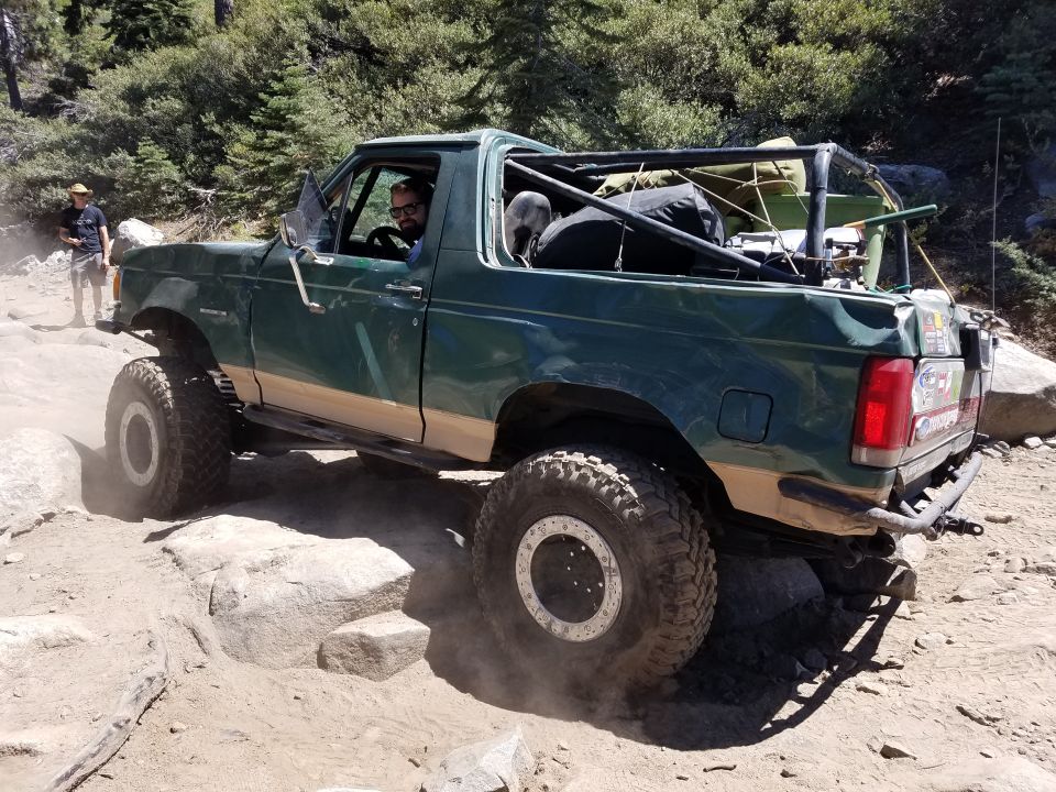 Green and tan 4x4 pickup truck on a rocky off-road trail.