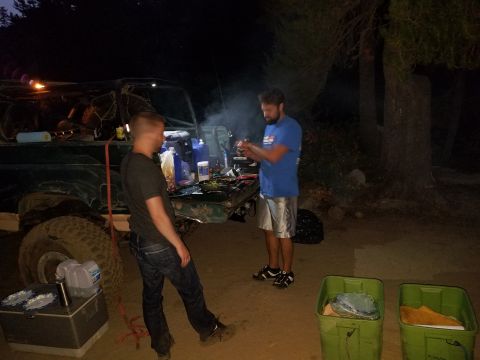 1968 Ford Bronco - People are gathered around the open rear of a vehicle at night, with various containers and equipment visible.