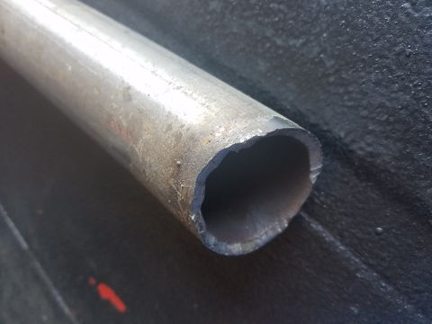 1968 Ford Bronco - A close-up view of the cut end of a metal pipe, likely a part of a vehicle's exhaust or frame. The pipe has a rough, uneven edge from being…