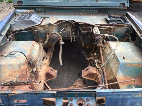 1967 Ford Bronco - The engine bay of a vehicle shows significant rust and exposed wiring, indicating it is in disrepair.