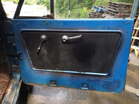 1967 Ford Bronco - Interior view of a weathered blue vehicle door with chrome door handles and window crank.