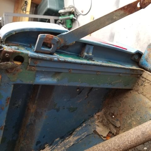 1967 Ford Bronco - This is a close-up view of the rusted metal frame of a blue vehicle, possibly a vintage Bronco, showing peeling paint and visible screws.