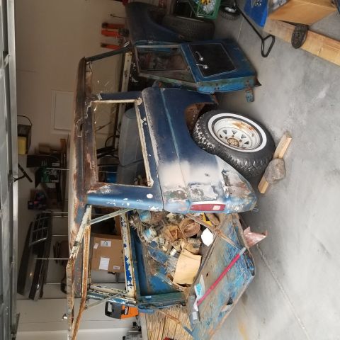 1967 Ford Bronco - A rusted, partially disassembled blue 1967 Ford Bronco is stored in a garage with various parts scattered around it. The vehicle is missing…