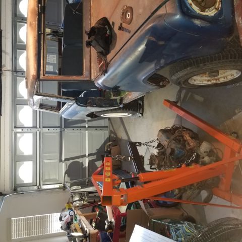 1967 Ford Bronco - A partially disassembled blue vehicle is in a garage, with an engine being lifted out by an orange engine hoist. The vehicle appears to be…