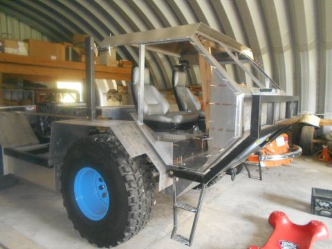 1992 Ford Bronco - A custom-built vehicle chassis with large tires and a metal frame for the cab is shown in a workshop setting. The vehicle has two bucket se…