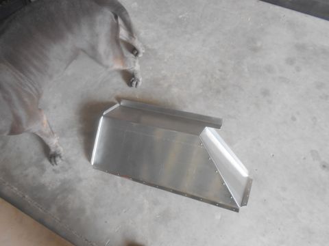 1992 Ford Bronco - A grey dog lies on a concrete floor next to a custom-fabricated aluminum component. The component appears to be a part of a vehicle or equi…