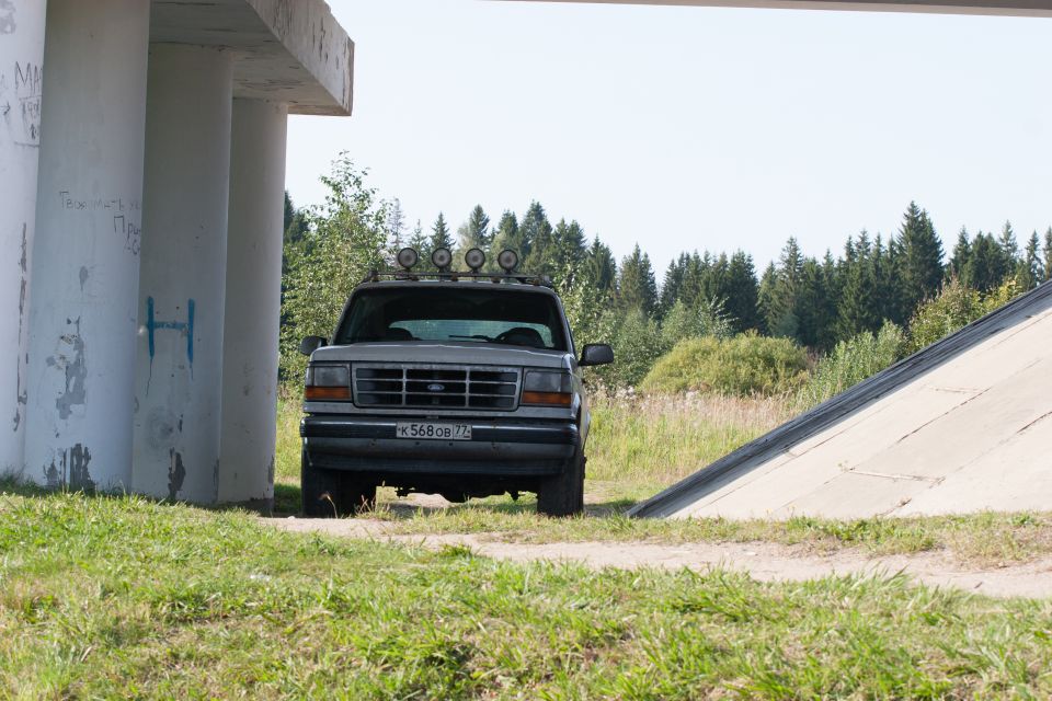 Silver 1993 Ford Bronco parked under a concrete overpass, front view.